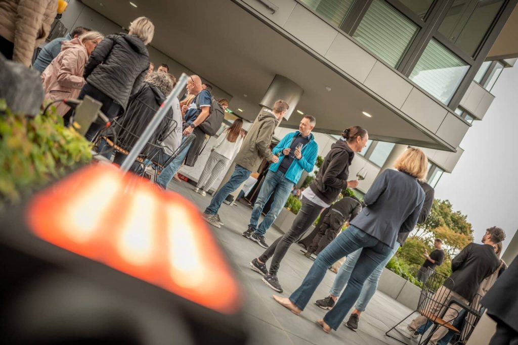 Menschen genießen zwangloses Afterwork-Treffen auf der Dachterrasse des Technopark Raaba.
