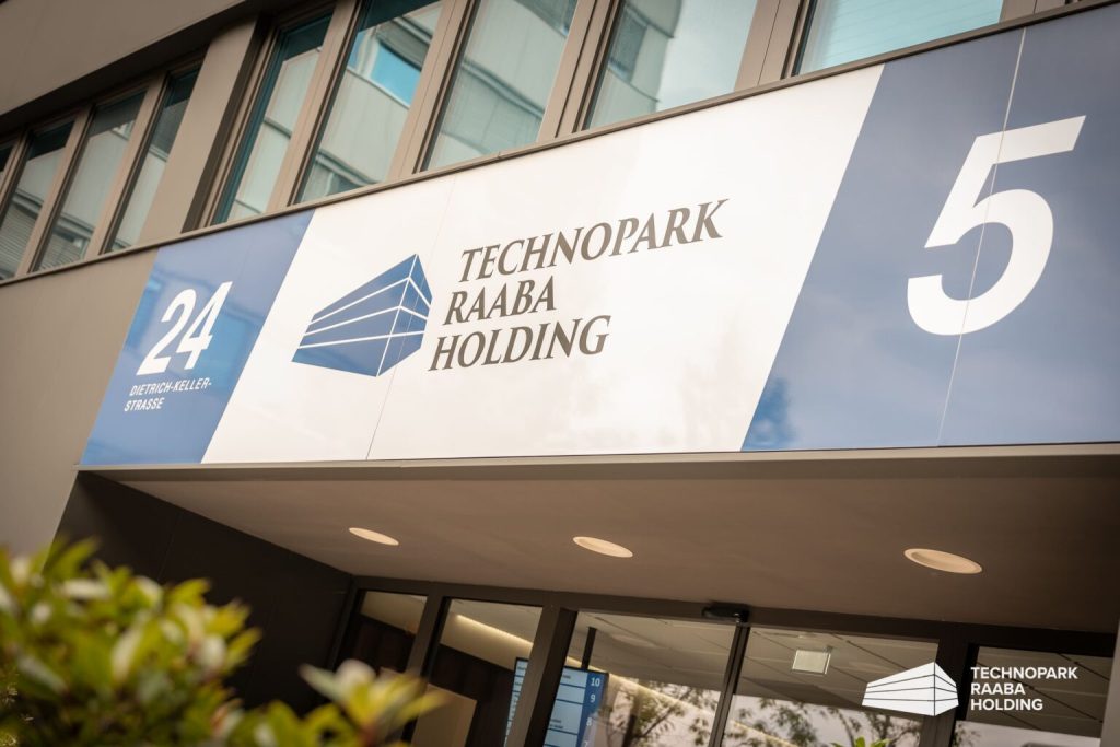 Eingang des Gebäudes mit Technopark Raaba Logo und Hausnummer, moderne Fassade im Hintergrund.