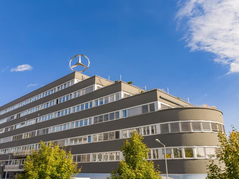 Modernes Gebäude mit charakteristischen abgerundeten Ecken und großen Fenstern unter blauem Himmel.