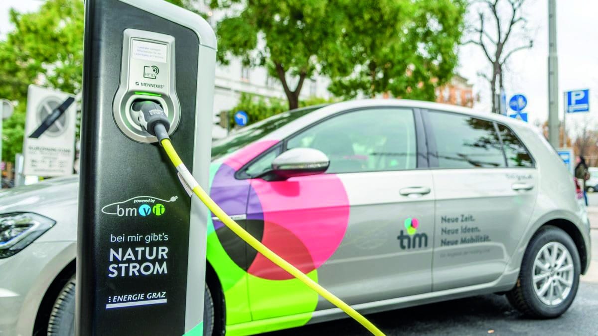 Elektroauto lädt an einer Ladestation im Technopark Raaba, im Hintergrund grüne Bäume.