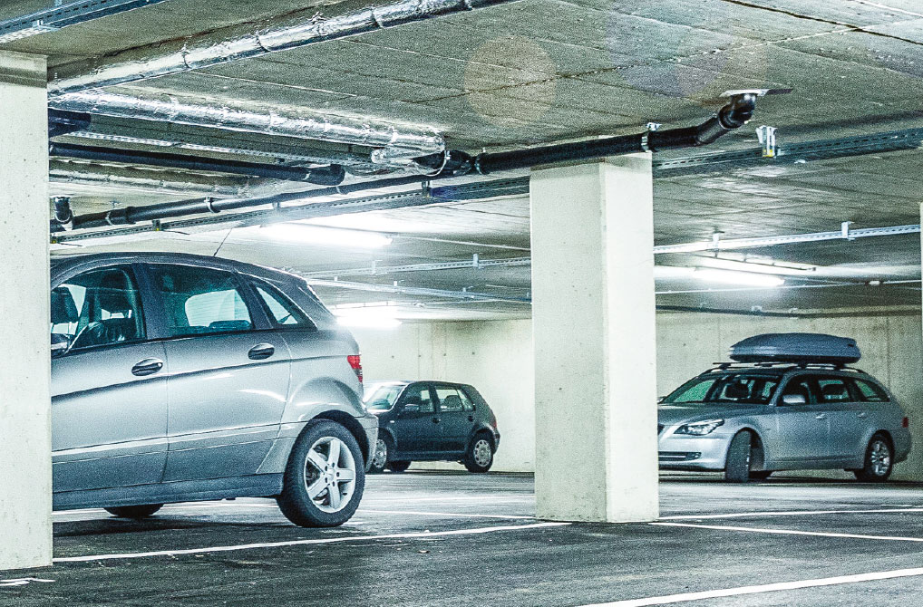 Tiefgarage mit geparkten Autos im Technopark Raaba, Betonwände und -säulen, moderne Beleuchtung.