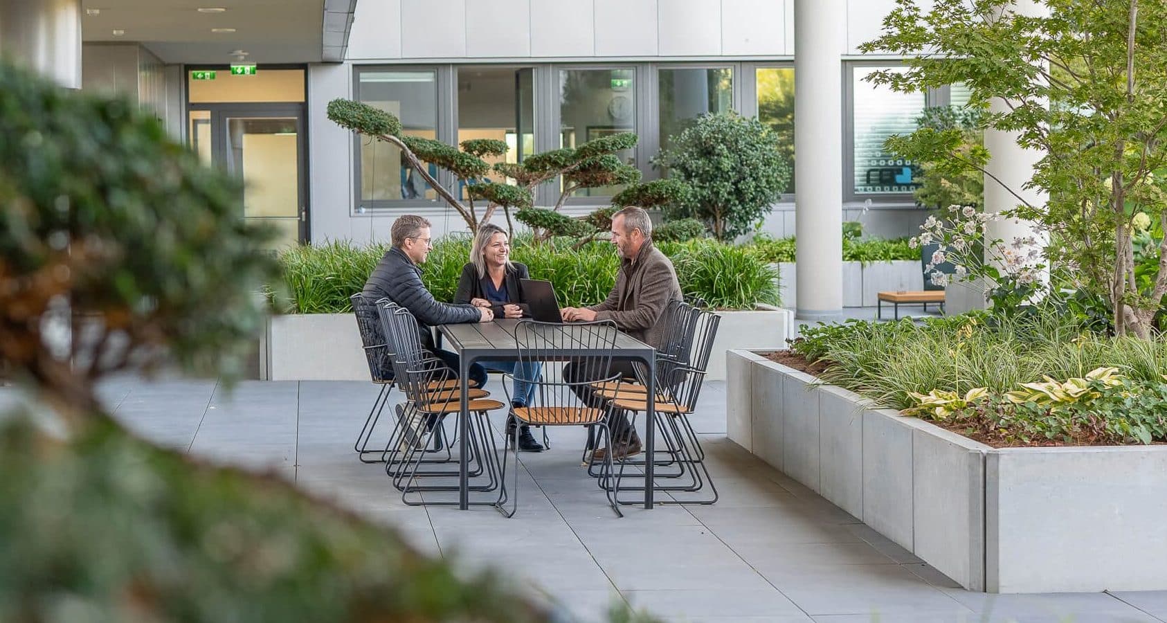 three people sitting around a table on a terace